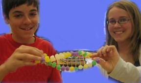 Photo shows two students holding a gumdrop and toothpick creation shaped like a DNA double helix.